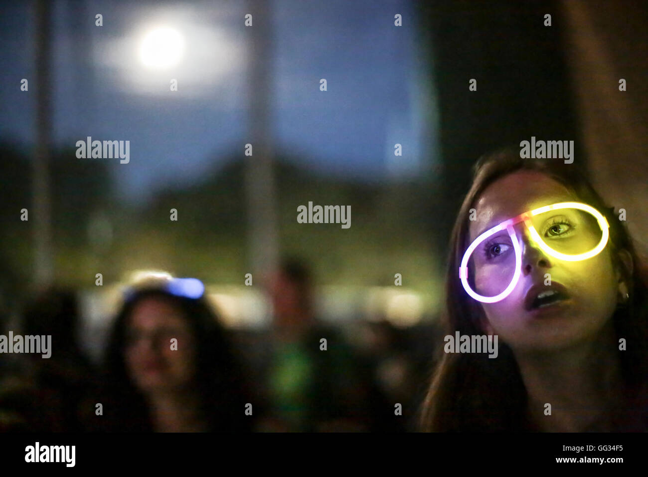 Ein Festival Goer, Lauren Peters, Soulwax im BBC 6Music Zelt mit leuchtenden Brille mit dem Mond im Hintergrund beobachten Stockfoto