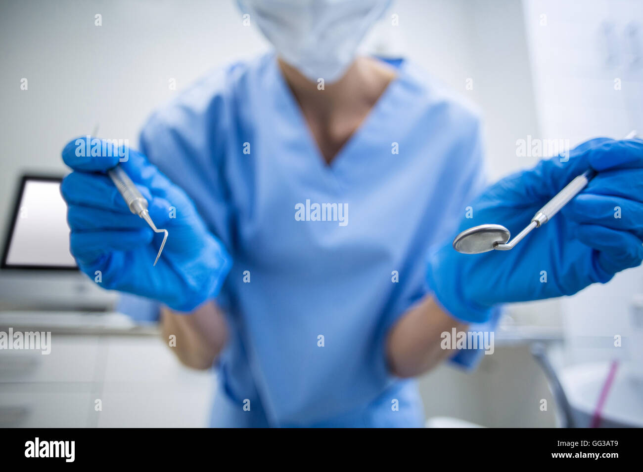 Zahnarzthelferin in OP-Maske hält Dentalwerkzeuge Stockfoto