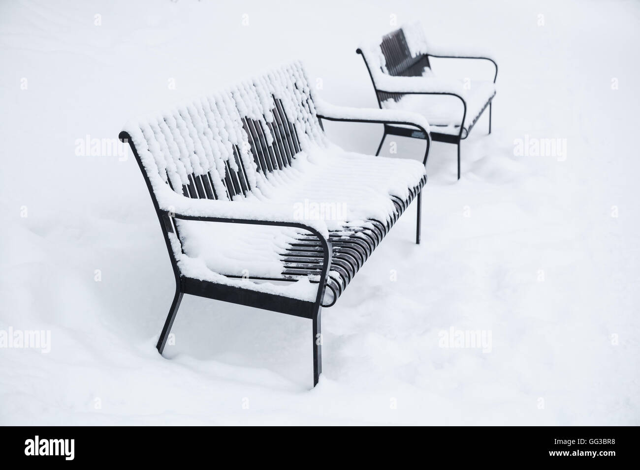 Zwei Outdoor-Metallbänke bedeckt mit Schnee im Winter Park. Turku, Finnland Stockfoto