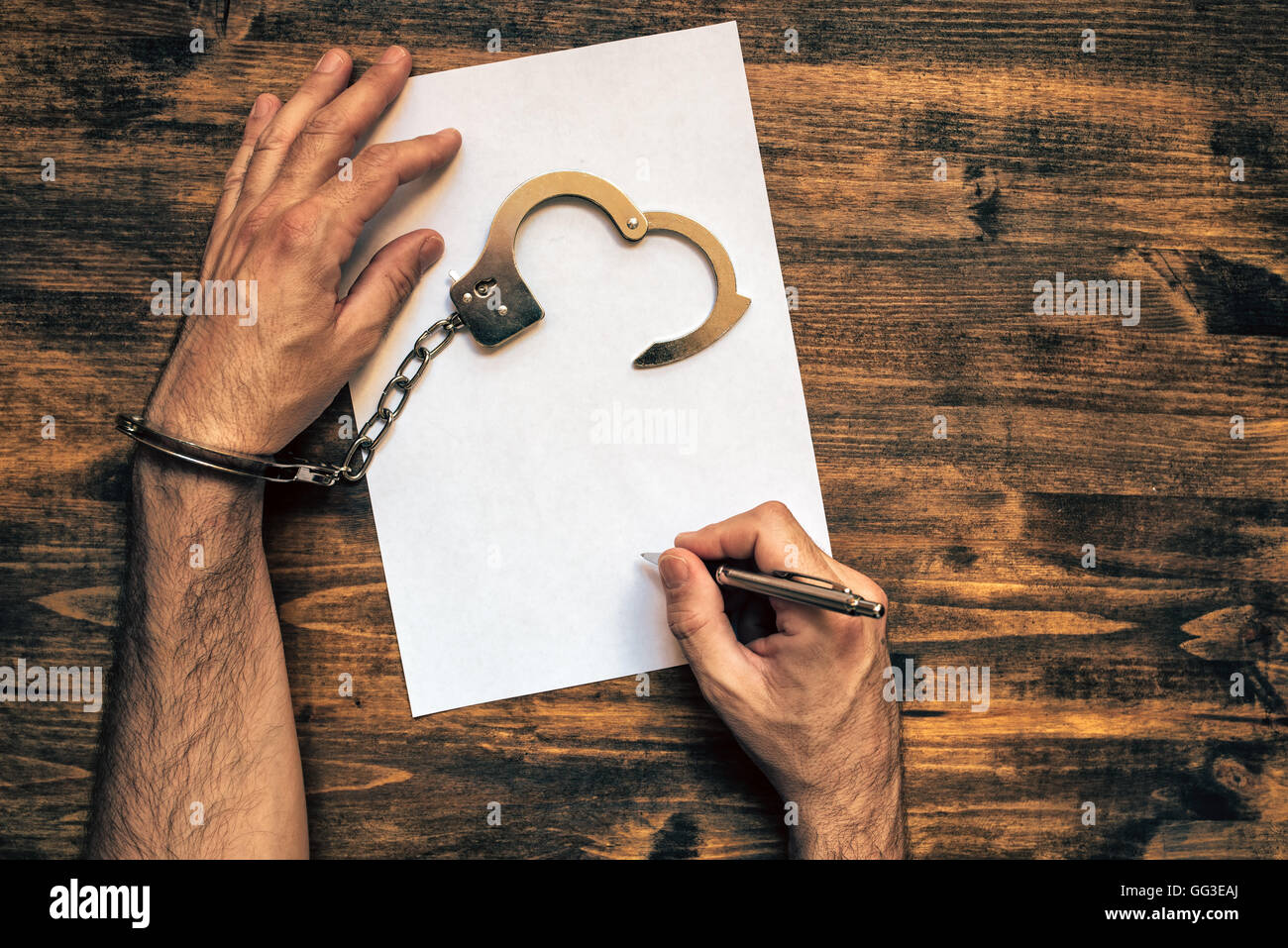 Männliche Hände gefesselt Draufsicht Unterzeichnung Beichte, der polizeilichen Ermittler Detektiv Schreibtisch Stockfoto