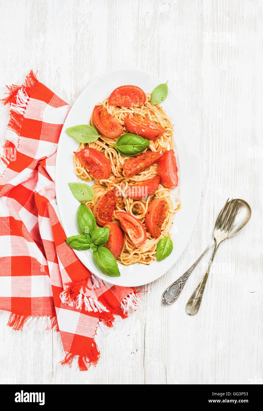 Spaghetti mit gebratenen Tomaten und Basilikum in weißem Holz Hintergrund Stockfoto