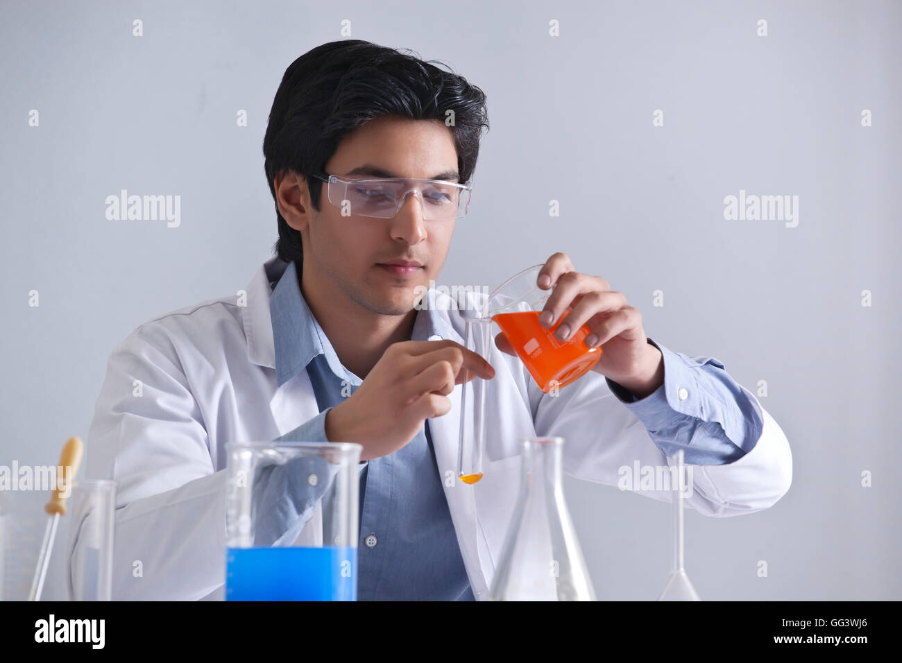 Junge Wissenschaftler, die Flüssigkeit in ein Reagenzglas gießen Stockfoto