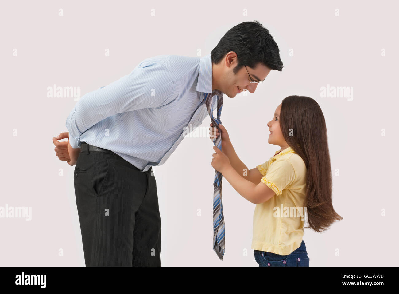 Junges Mädchen des Vaters Krawatte über farbigen Hintergrund anpassen Stockfoto