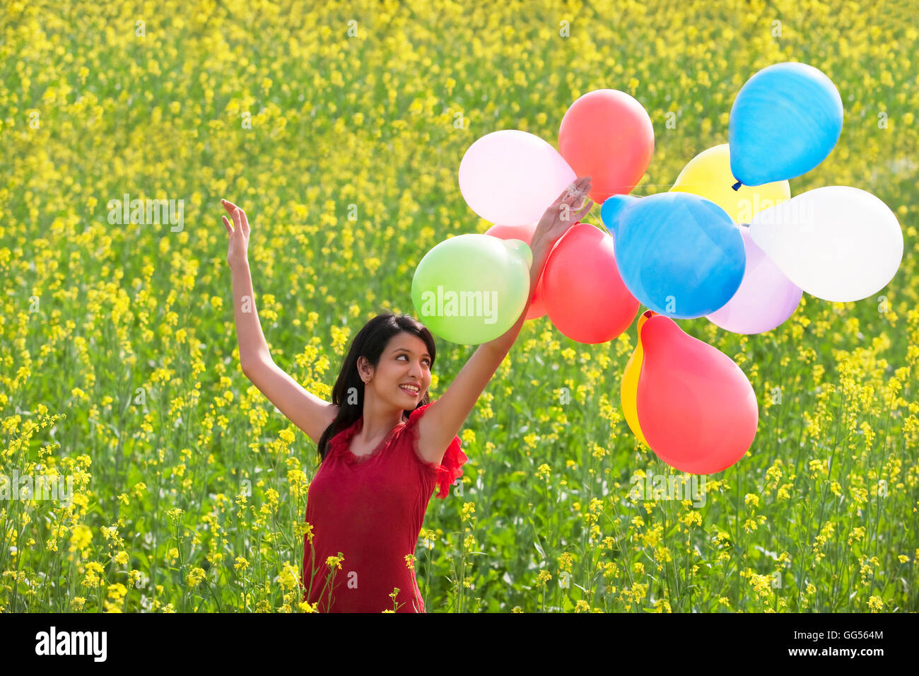 Junge Frau mit Luftballons in einem Feld Stockfoto