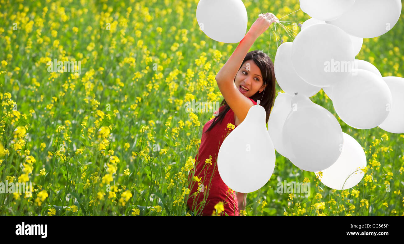 Junge Frau mit Luftballons in einem Feld Stockfoto