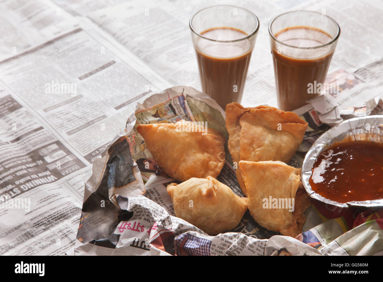 Erhöhte Ansicht von frischen Samosas, Chutney und Tee auf Tisch Stockfoto