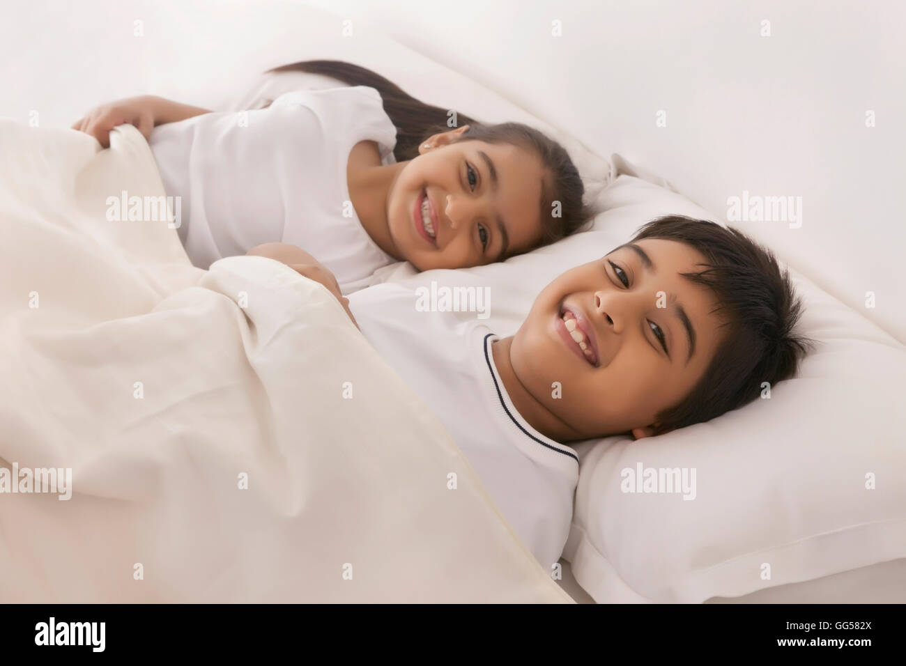 Porträt des Lächelns, Bruder und Schwester im Bett schlafen Stockfotografie...