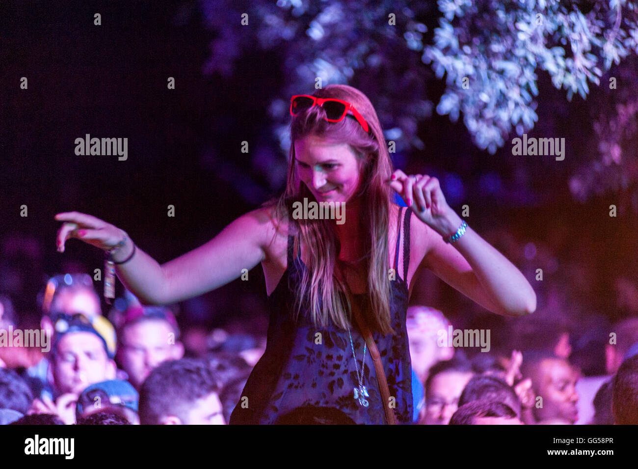 Musik-Festival. Menschen, die das Musikfestival am Meer in Kroatien genießen. Mädchen tanzen auf jemanden Schultern. Stockfoto