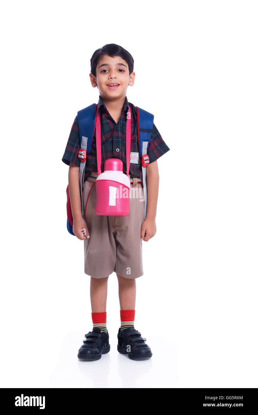 Glückliches Kind verkleidet in der Schule einheitliche Stellung vor weißem Hintergrund Stockfoto