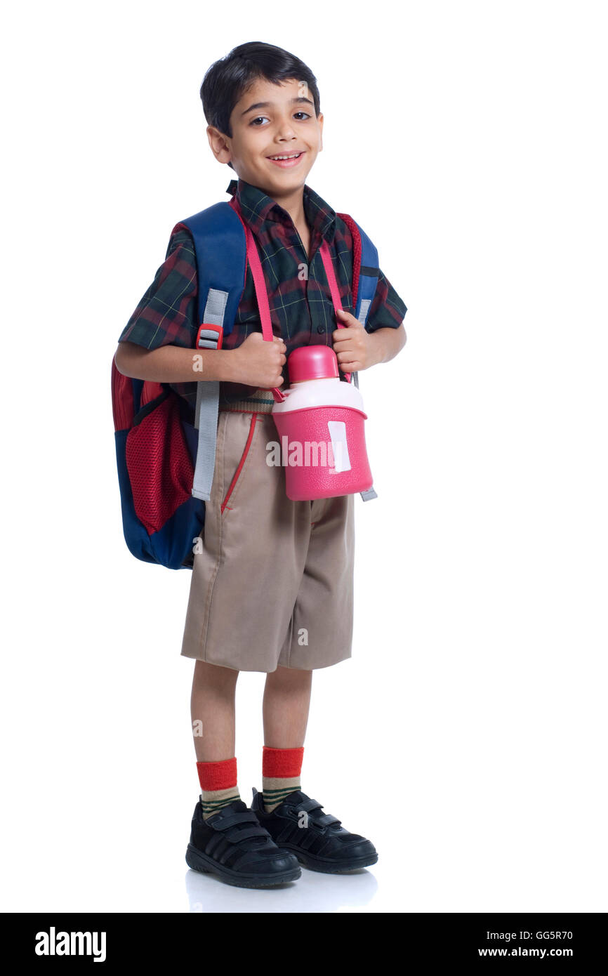 Lächelnde Schuljunge stehend mit Buch Tasche und Flasche Wasser vor weißem Hintergrund Stockfoto
