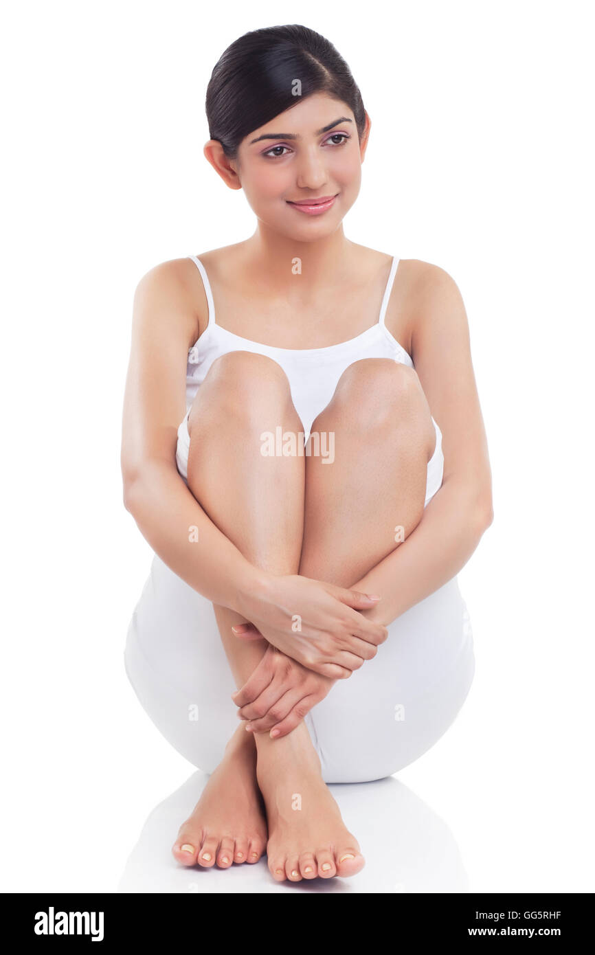 Lächelnde junge Frau rieb ihr Bein über weißem Hintergrund Stockfoto