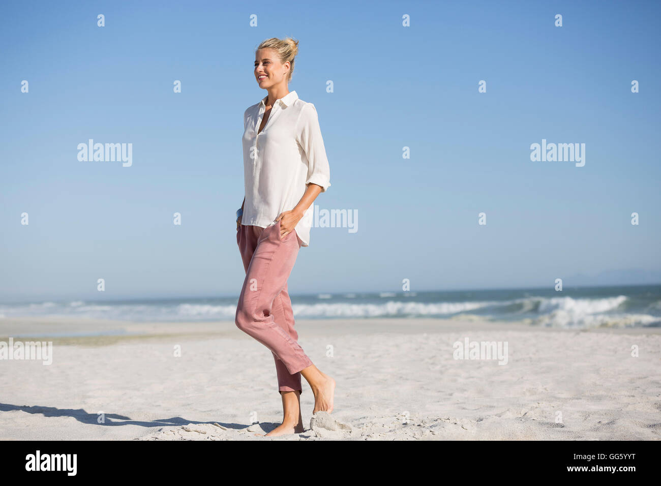 Schöne junge Frau, die zu Fuß am Sonnenstrand Stockfoto