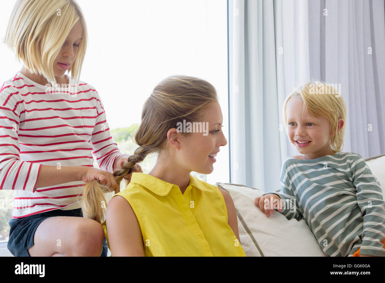 Glückliche Mutter und Kinder sitzen auf der Couch im Wohnzimmer Stockfoto