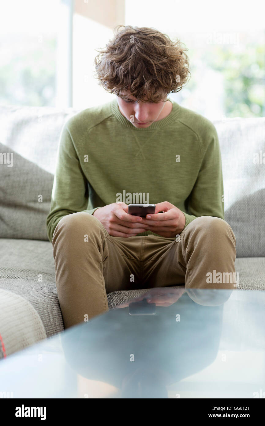 Teenager mit Telefon im Wohnzimmer Stockfoto