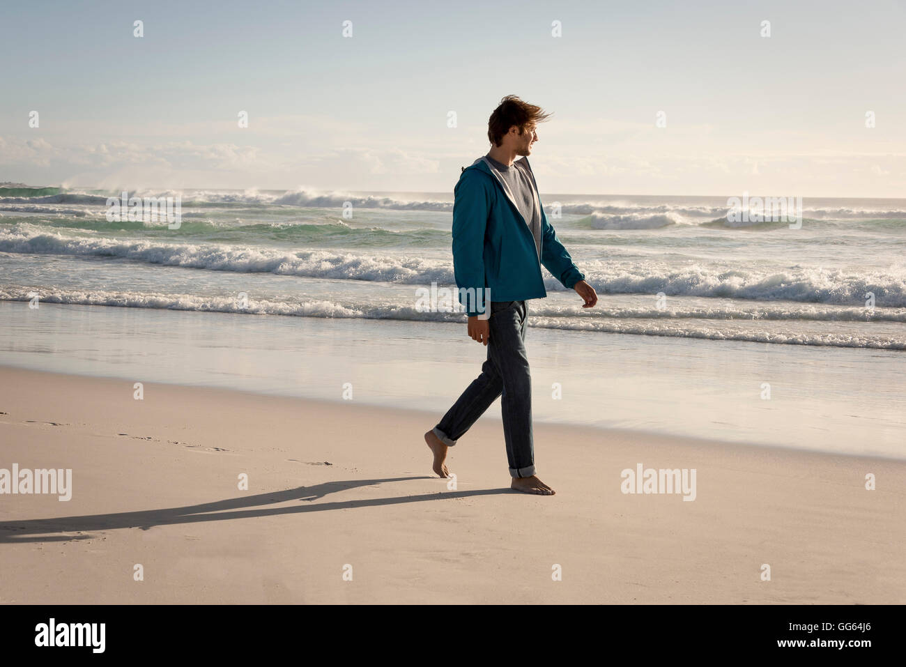 Glücklicher junger Mann zu Fuß am Strand Stockfoto