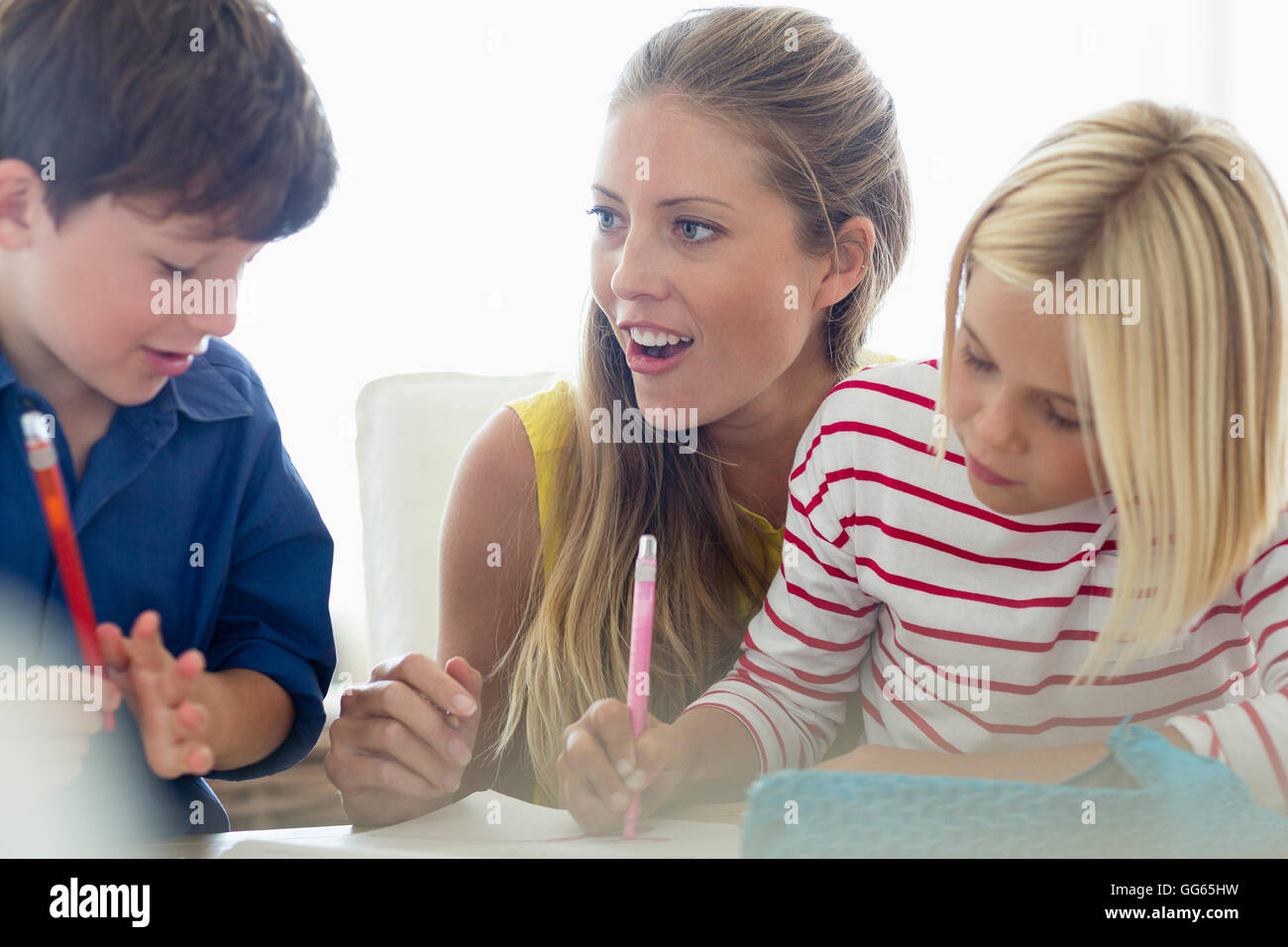 Fröhliche Frau, die ihre Kinder zu Hause unterrichten Stockfoto