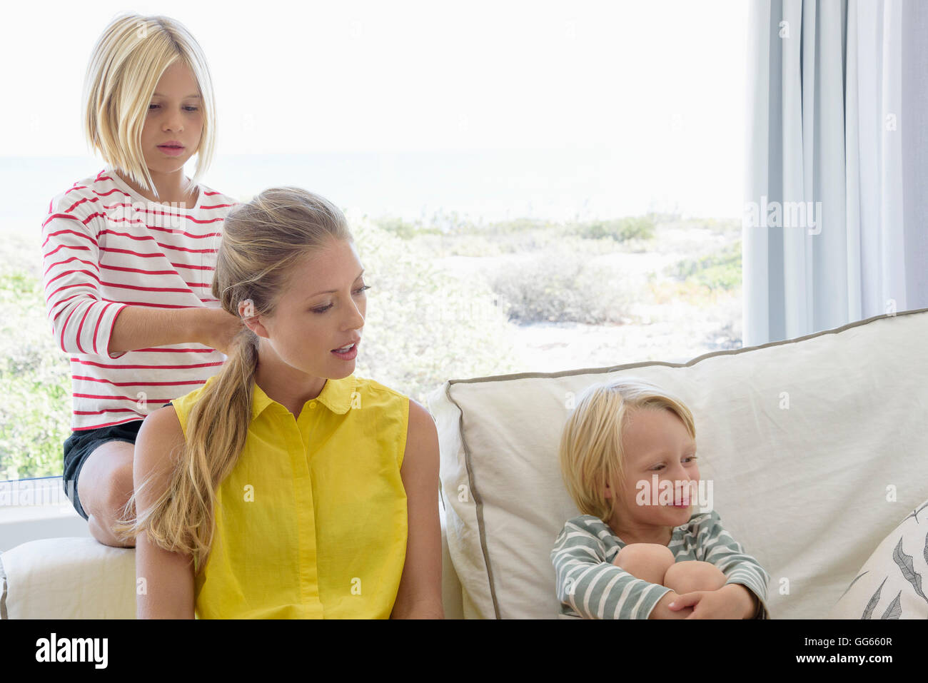 Glückliche Mutter und Kinder sitzen auf der Couch im Wohnzimmer Stockfoto