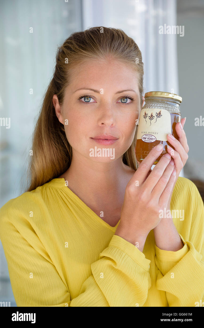 Porträt einer schönen Frau durchlöchern ein Glas Honig Stockfoto