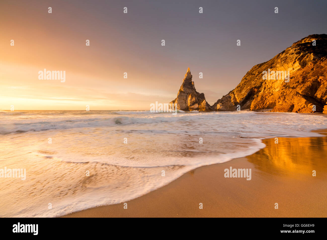 Goldenen Reflexen von den Klippen am Strand von Praia da Ursa bei Sonnenuntergang, vom Meer umspült, Cabo da Roca, Colares, Sintra, Portugal Stockfoto