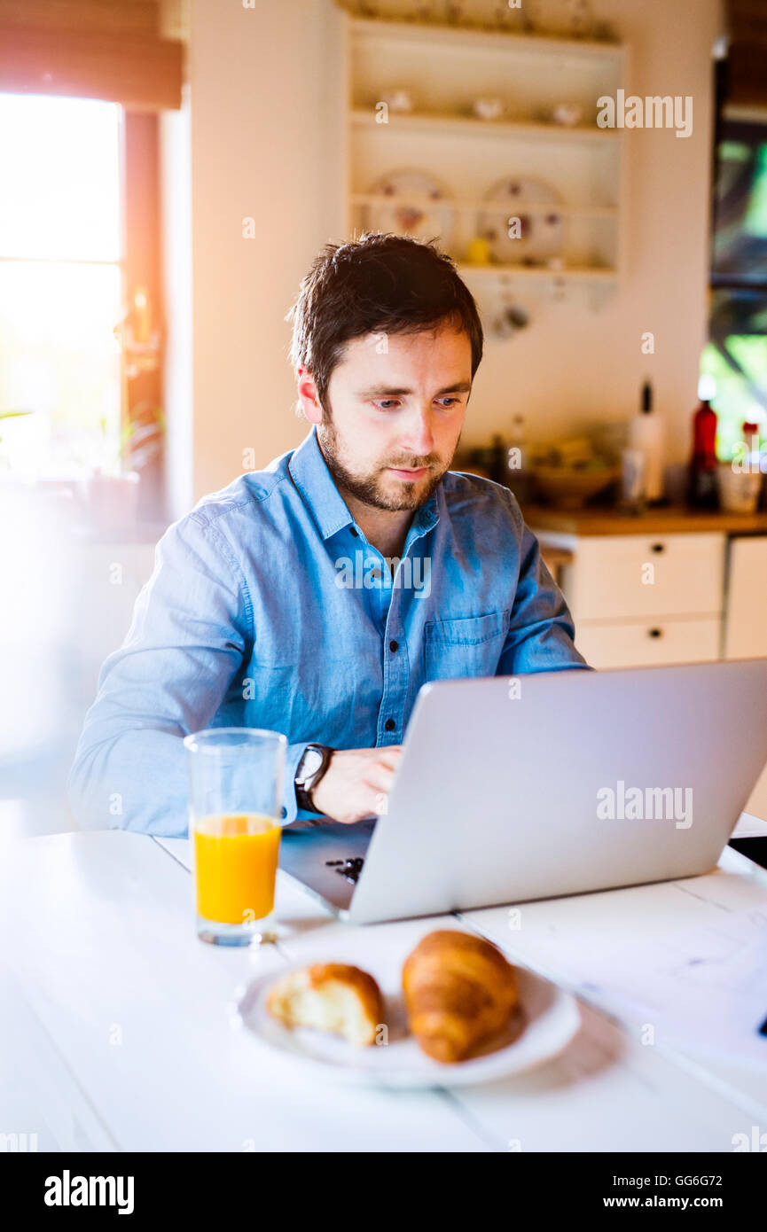 Mann am Schreibtisch arbeiten von zu Hause aus auf laptop Stockfoto