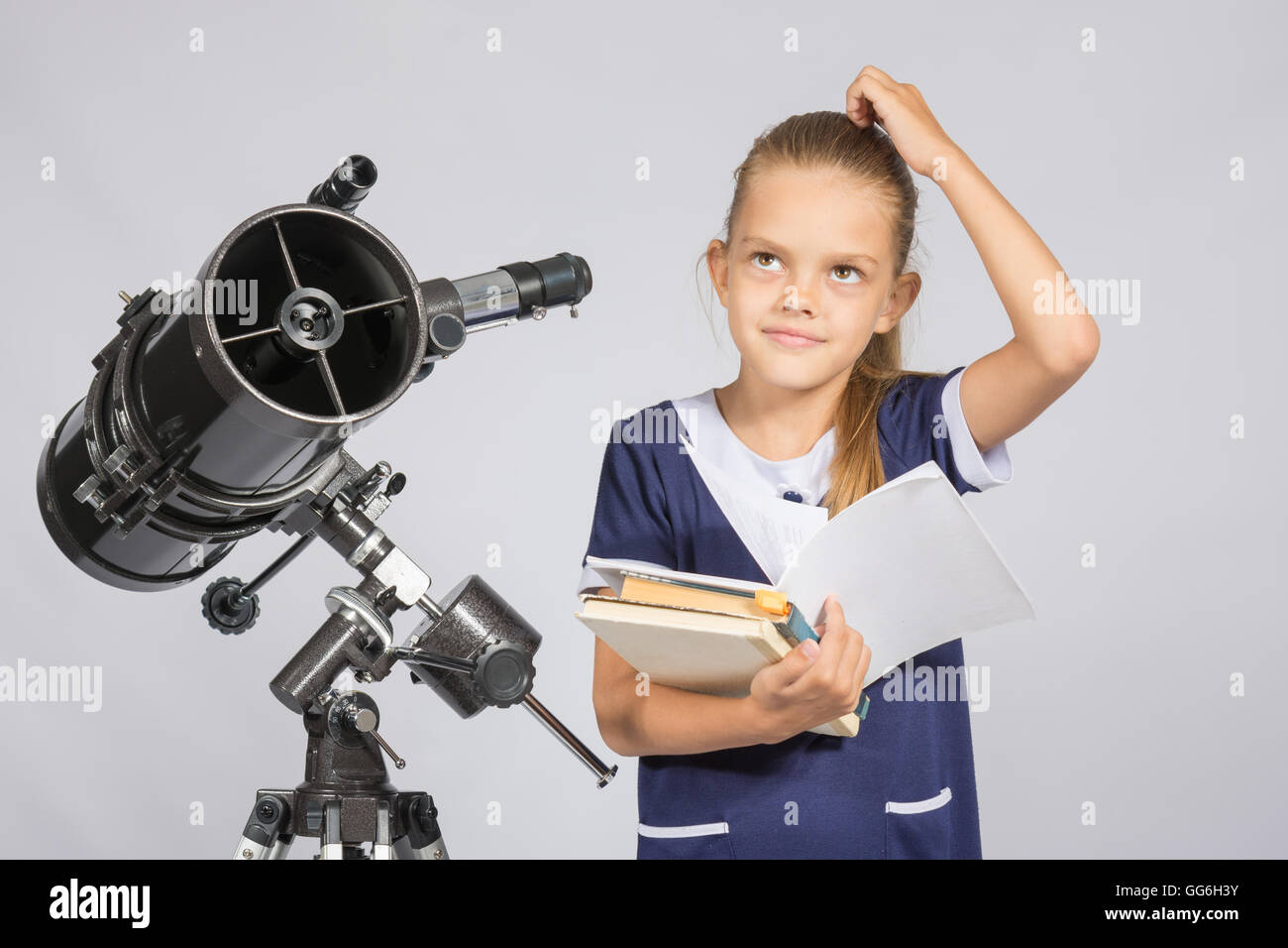 Schulmädchen gefragt und gesucht bis zu lesen ein Lehrbuch stehen am Teleskop Stockfoto