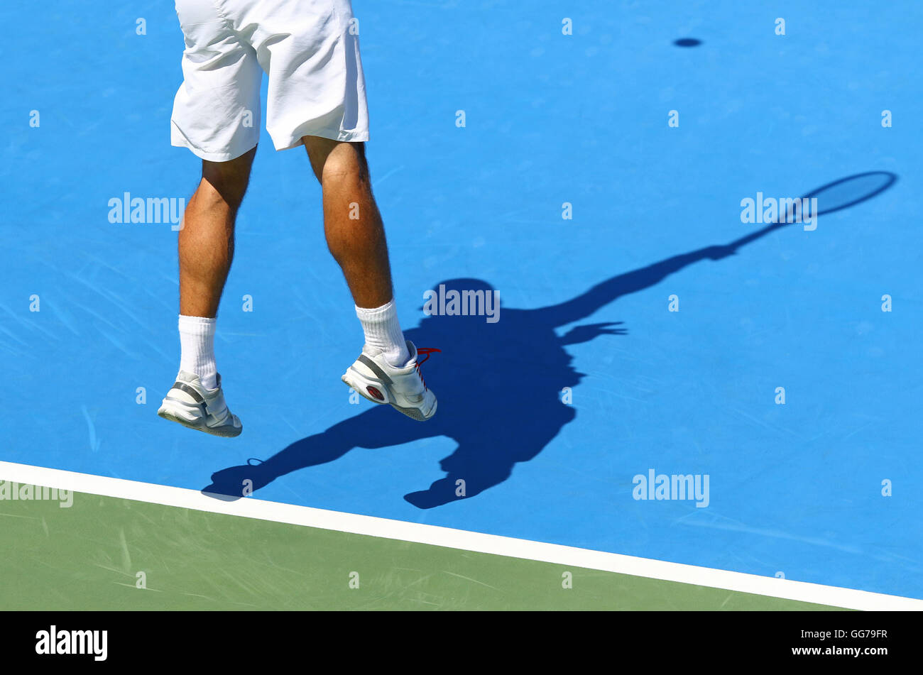 Tennis-Spieler dient den Ball (Schatten der Spieler auf dem Hartplatz) Stockfoto