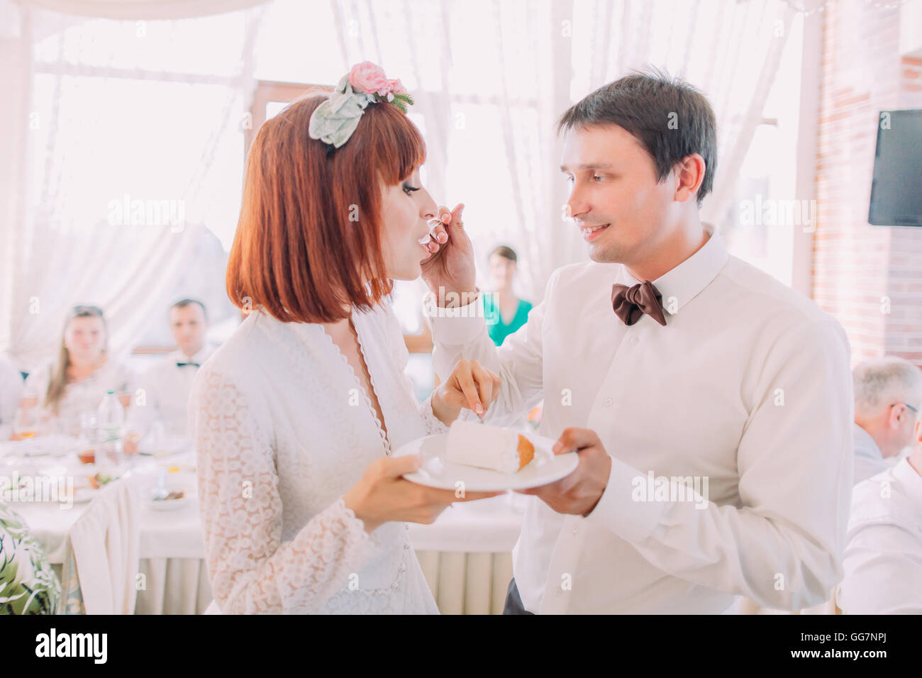 Nahaufnahme des lächelnden Bräutigam seine Braut mit einer Hochzeitstorte, drinnen zu füttern Stockfoto