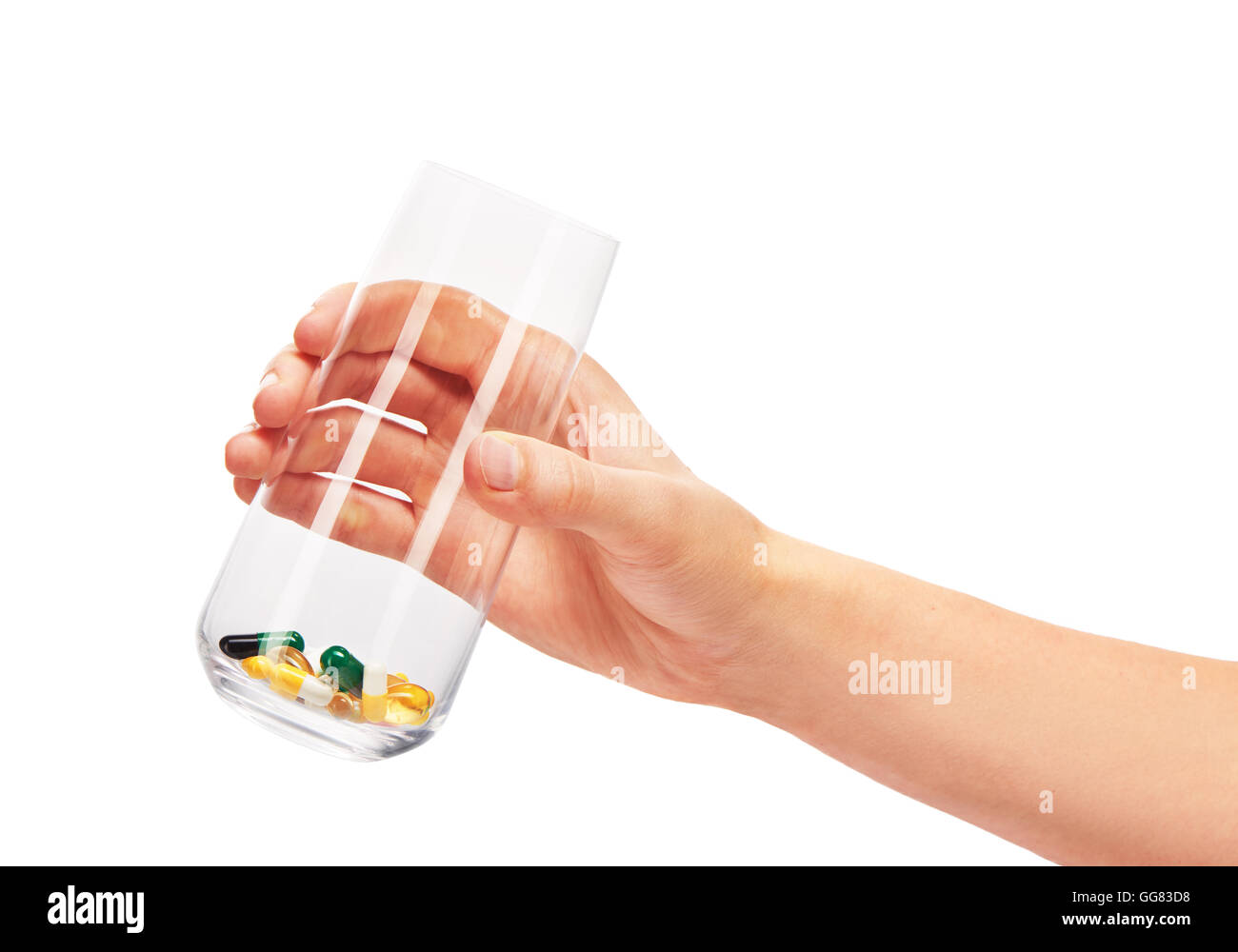 Nahaufnahme von weiblicher Hand hält sauber transparent Trinkglas mit Haufen von verschiedenen Tabletten und Kapseln gegen weiß Stockfoto