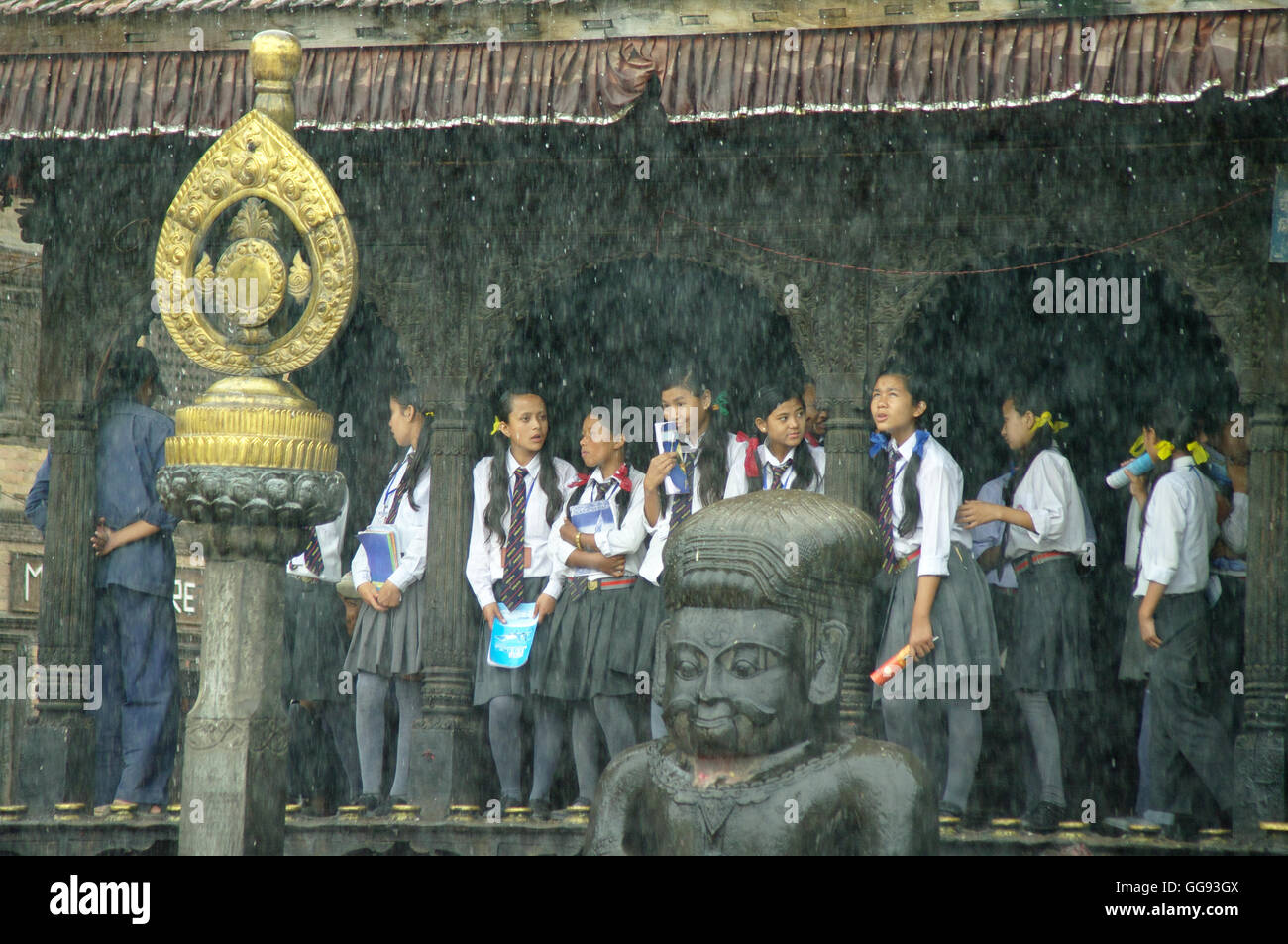 KATHMANDU, ca. AUGUST 2012 - junge Studenten Unterschlupf vor dem Monsunregen in einem Tempel, ca. August 2012 in Kathmandu. Stockfoto