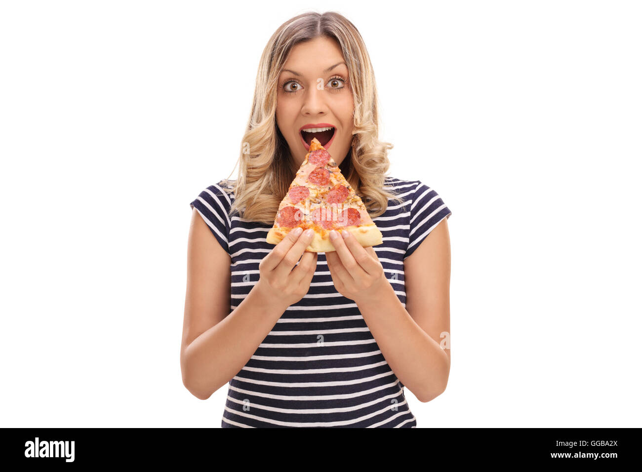 Junge Frau mit einem Stück Pizza und schaut in die Kamera, die isoliert auf weißem Hintergrund Stockfoto