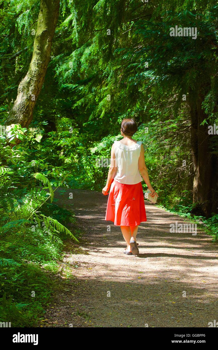 Frau zu Fuß auf Weg im Wald. Gibside, Rowlands Gill, Gateshead, Tyne & Verschleiß, England, Vereinigtes Königreich, Großbritannien, Europa. Stockfoto