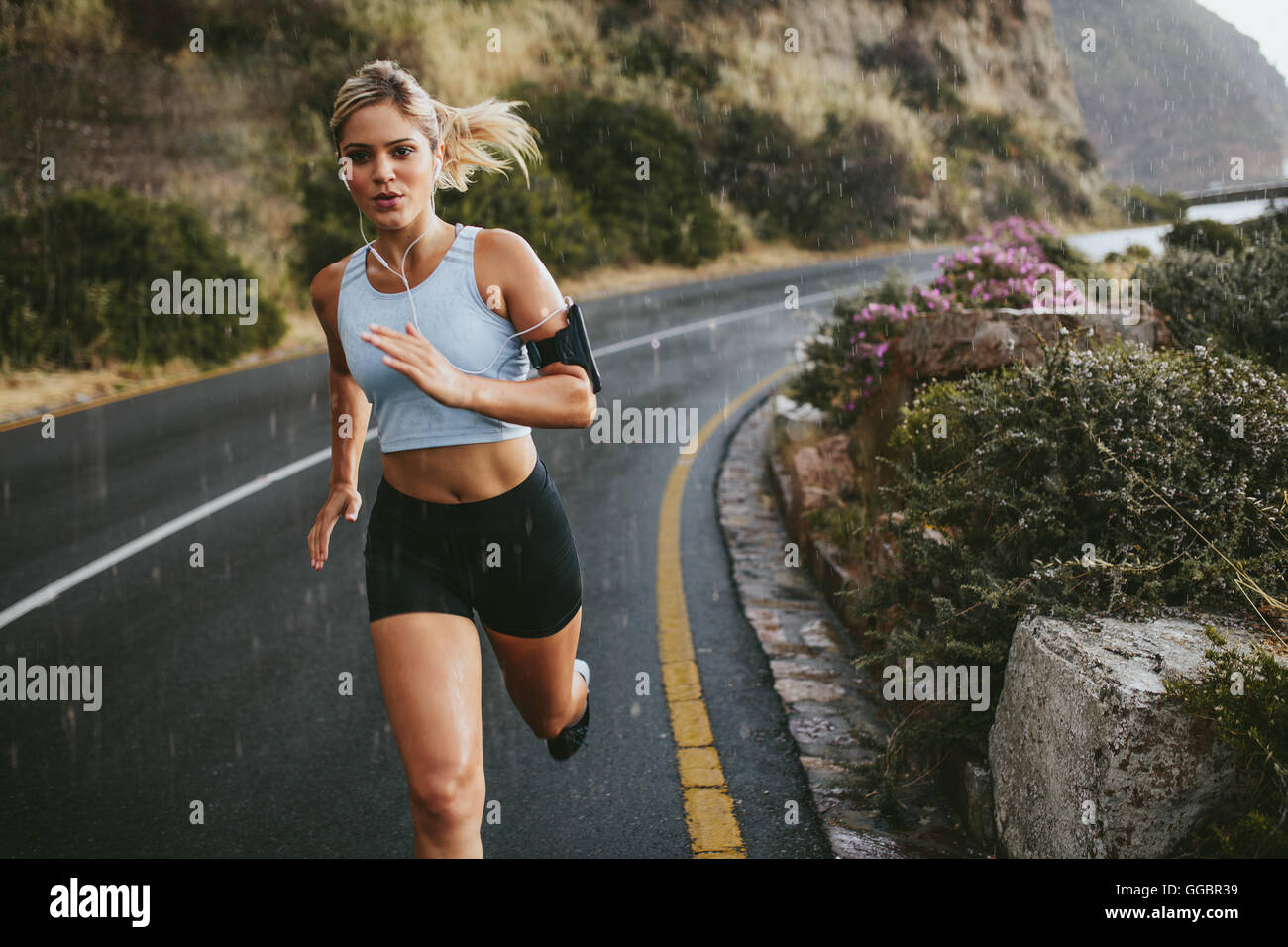 Sportlerin im freien laufen auf Autobahn. Schöne junge Frau, die Ausbildung an einem regnerischen Tag ausgeführt. Stockfoto