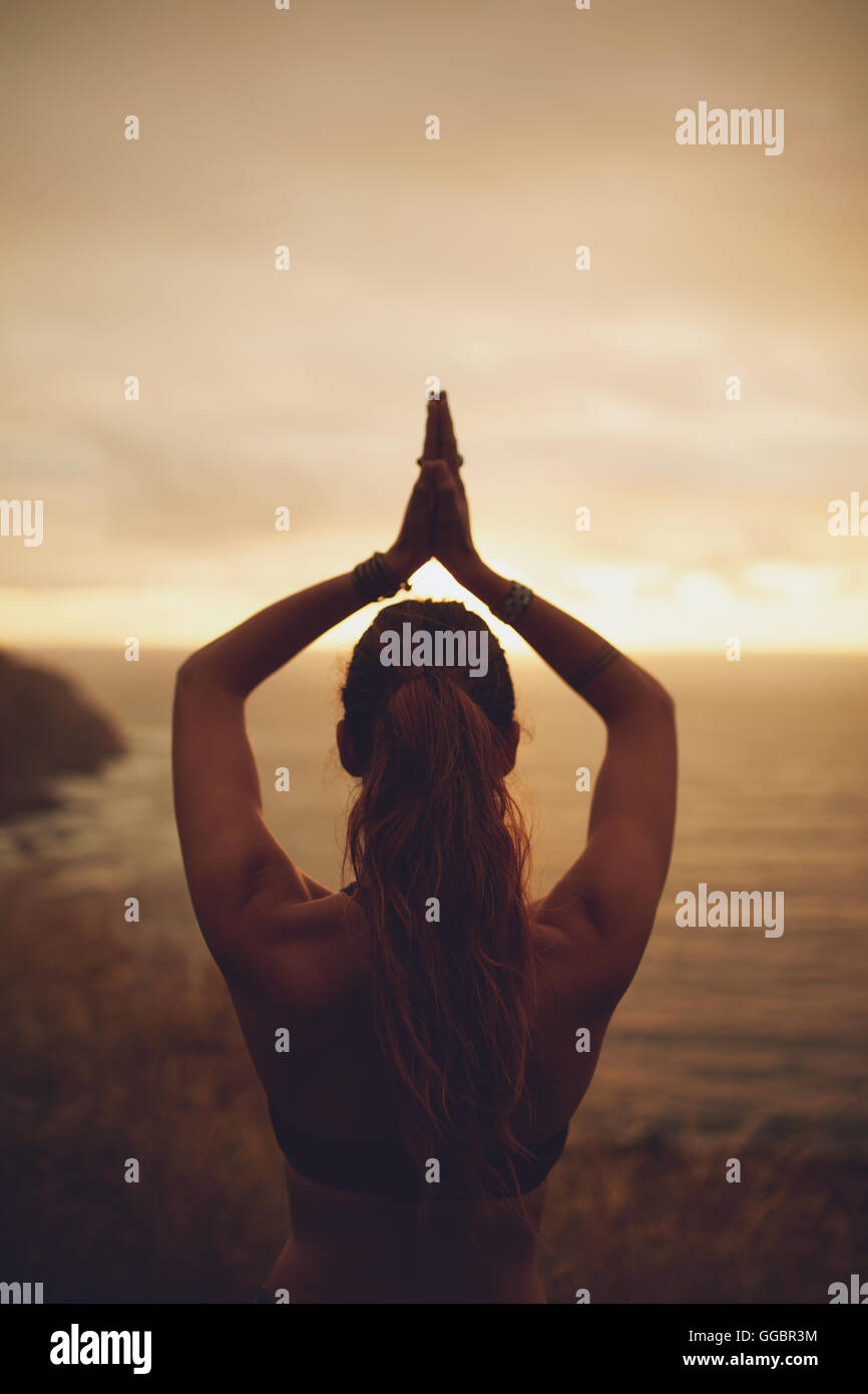Rückansicht Aufnahme Fitness Frau Yoga während des Sonnenuntergangs zu tun. Weibliche stehend mit den Händen verbunden Aufwand. Stockfoto