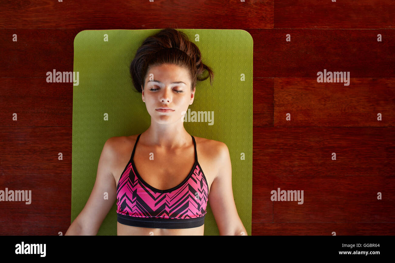 Draufsicht der attraktive junge Frau entspannt auf Fitness-Matte mit ihren Augen geschlossen bei Yoga Gym. Gesunde Frau in Savasana Pose bei Stockfoto