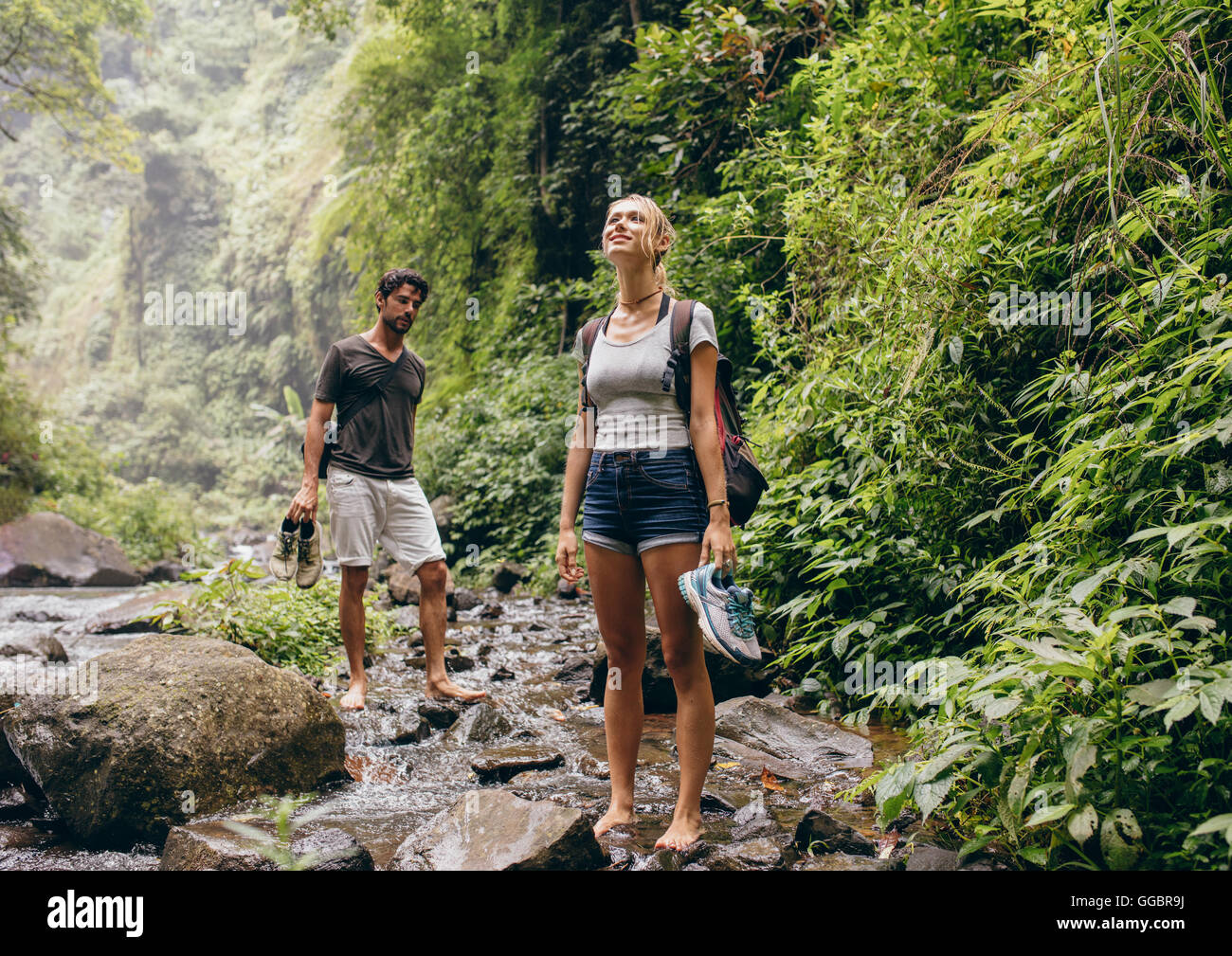 Paar über den Bach. Mann und Frau im Wald zu Fuß durch einen Bach. Touristischer Natur wandern. Stockfoto