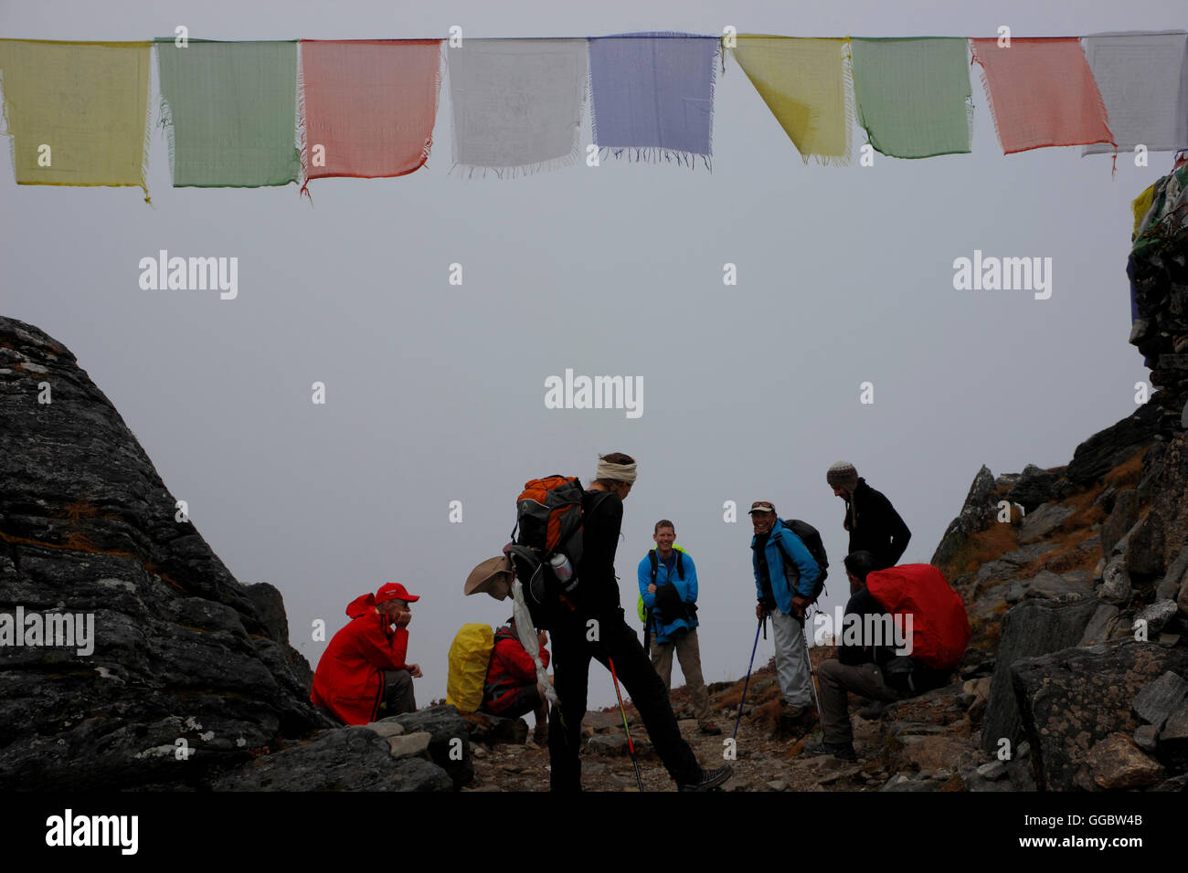 Ansicht von Wanderern und Sherpa unterwegs Zatrwa La Pass im Nebel in High Point mit tibetischen Gebetsfahnen Stockfoto
