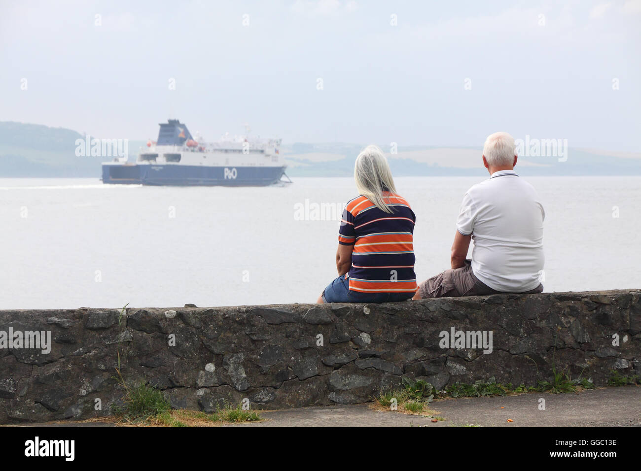 Paar mittleren Alters sehen die P & O Fähre Segeln in Loch Ryan in der Nähe von Cairnryan, Schottland Stockfoto