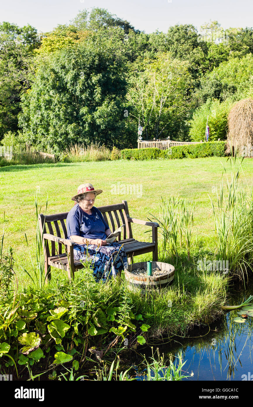 Lady sitzen Lesung in einem ruhigen Garten Stockfoto