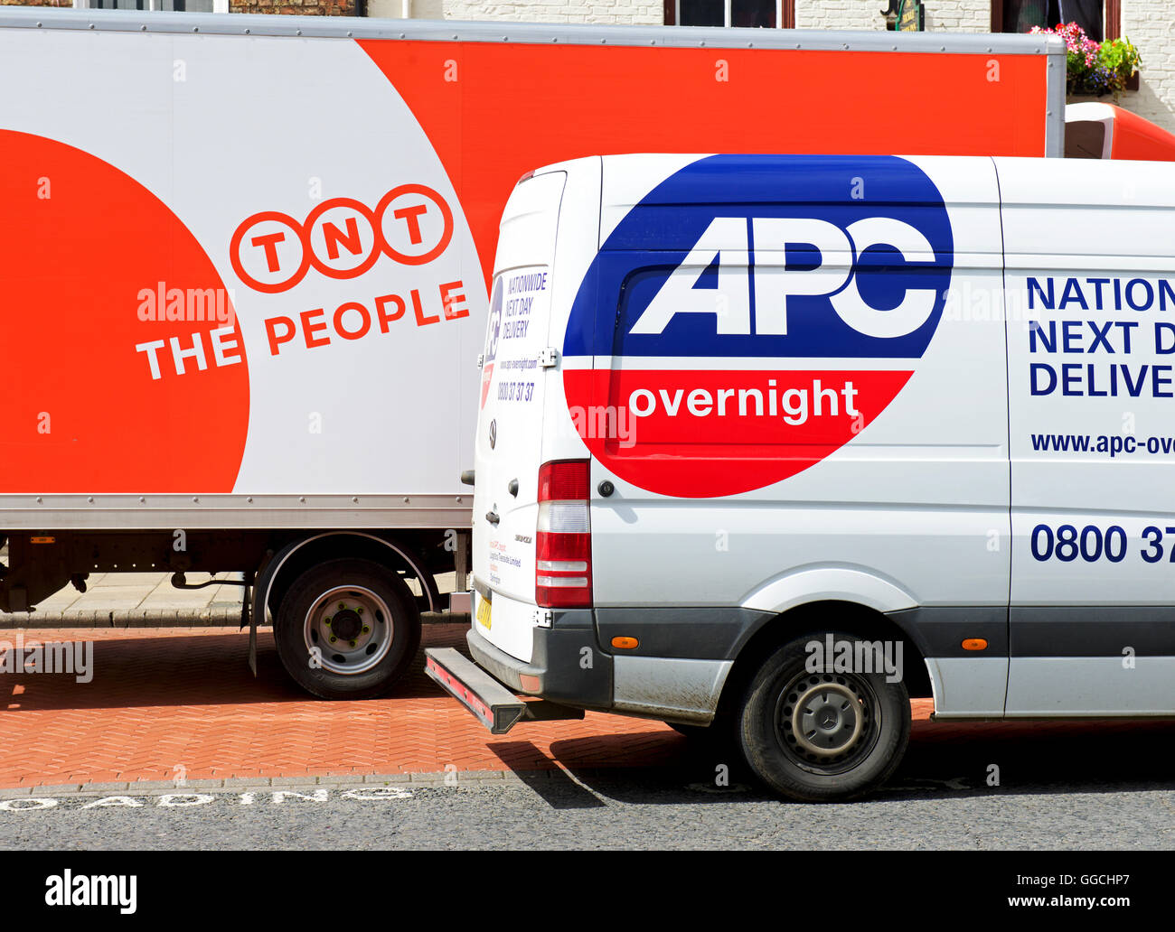 Zwei Lieferwagen - TNT und APC - geparkt zusammen, England UK Stockfoto