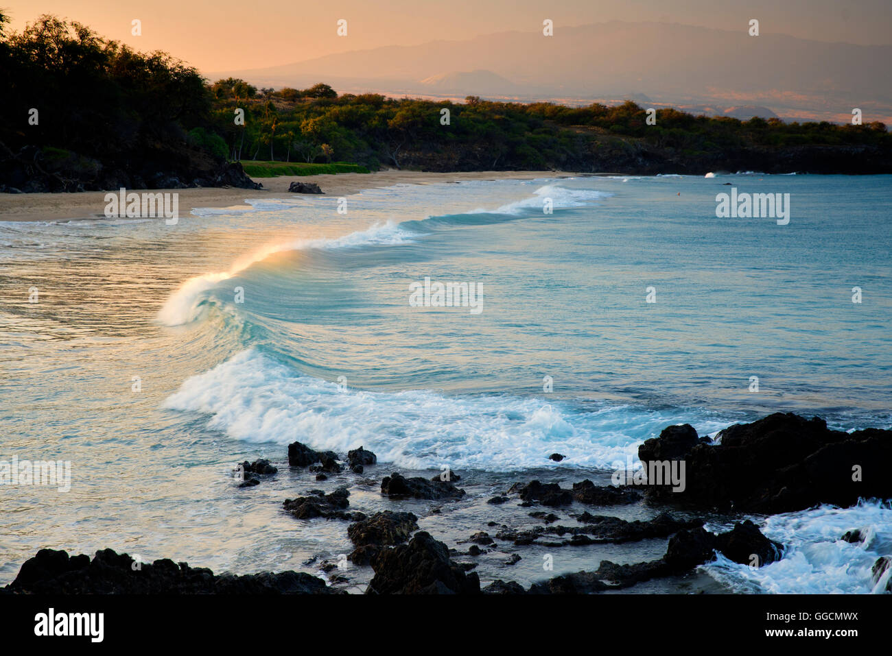 Wellen und Sonnenaufgang am Hapuna Beach mit Hualalai Vulkan im Hintergrund. Hawaiis Big Island Stockfoto