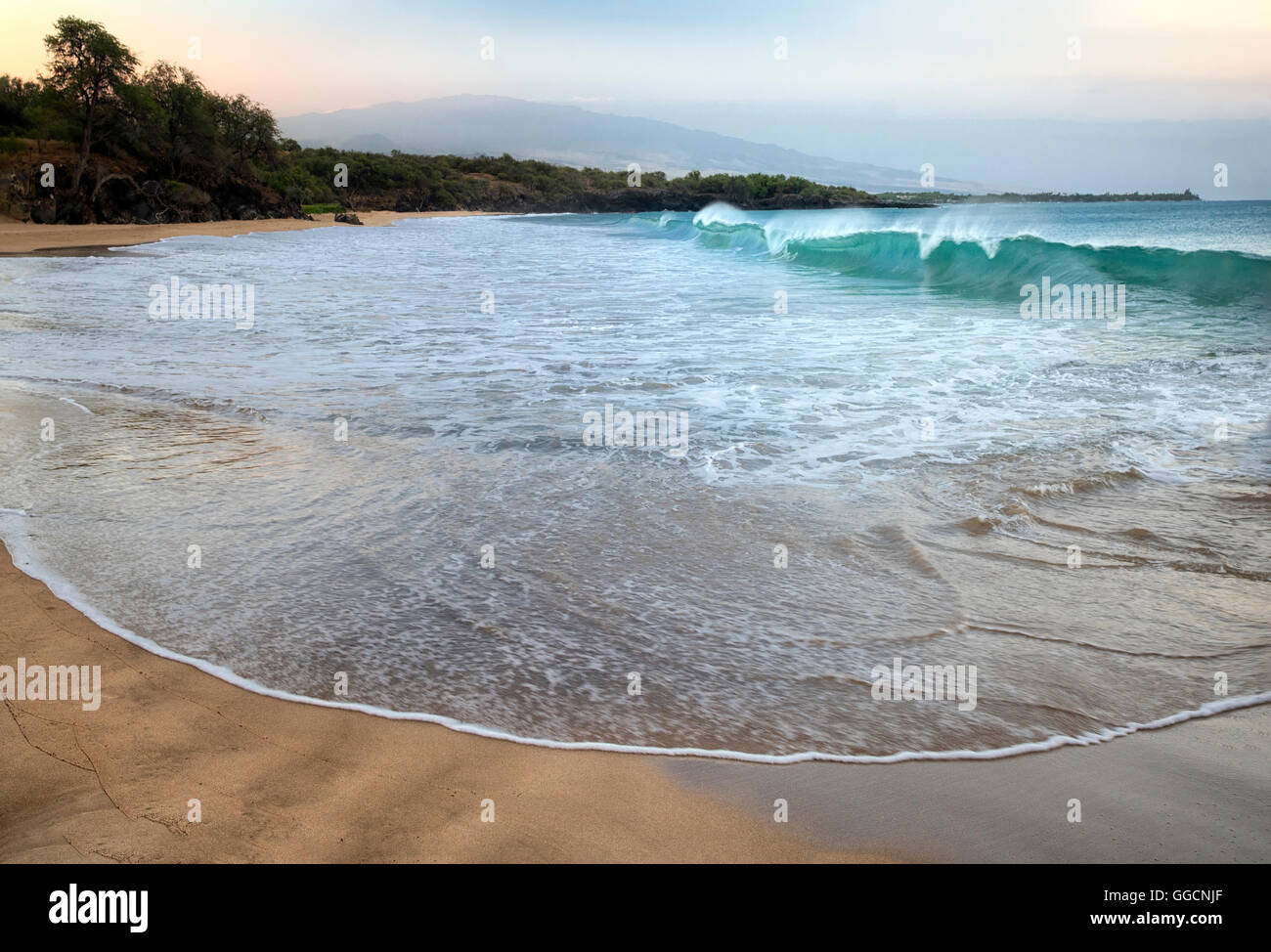 Wellen und Sonnenaufgang am Hapuna Beach mit Hualalai Vulkan im Hintergrund. Hawaiis Big Island Stockfoto