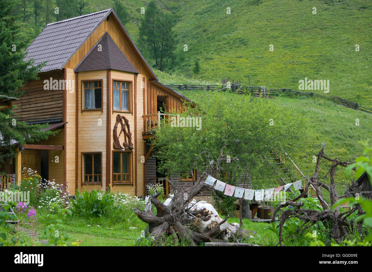 Das Haus aus Holz unter den Hügeln und Bergen, das Haus aus Holz, Berge, ein Rasen, Hügel, der Natur, eine Landschaft, ein Rasen Stockfoto