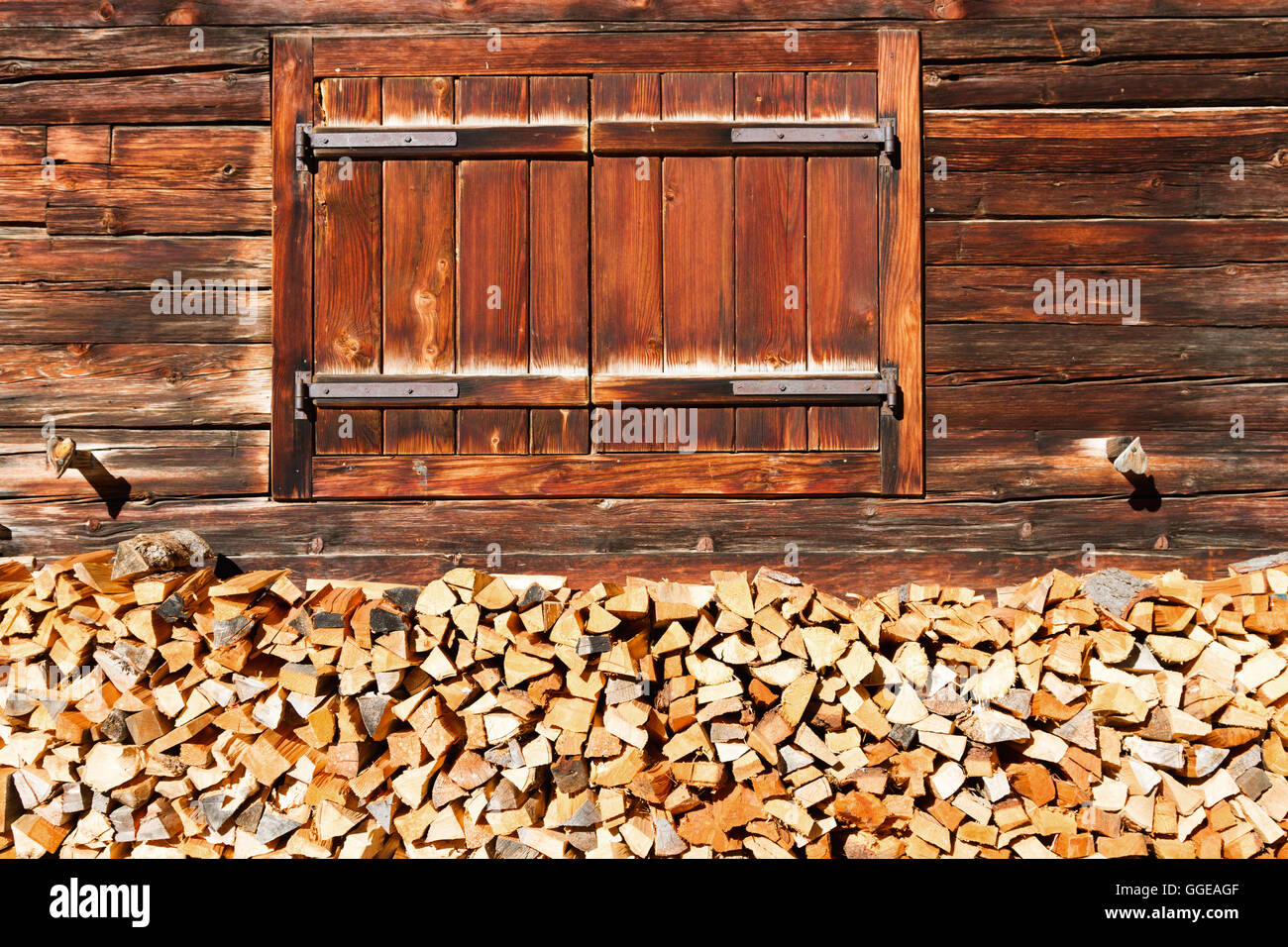 Geschlossenem Fenster und gestapelte Holz der alten Almhütte. Alpine Landschaft. Stockfoto