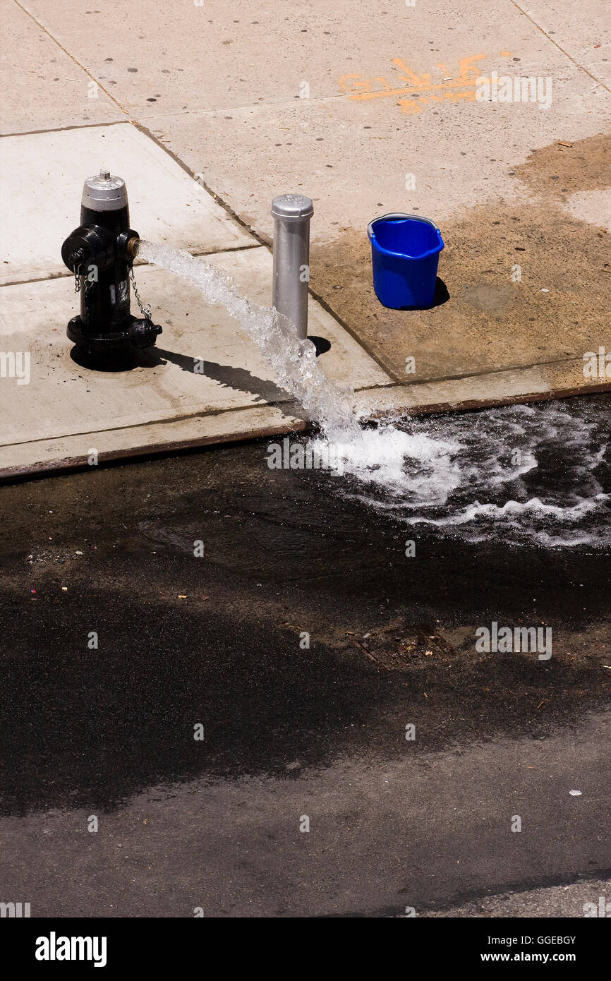 Offenen Hydranten auf dem Bürgersteig schießt einen Strom von Wasser in der Straße an einem heißen Sommertag Stockfoto