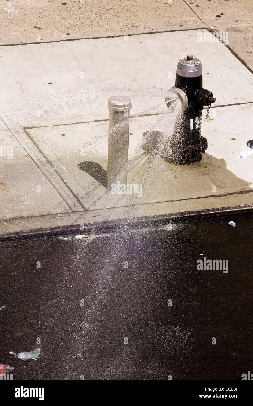 Offenen Hydranten mit Spray cap Düse schießen Ströme von Wasser auf die Straße an einem heißen Sommertag Stockfoto