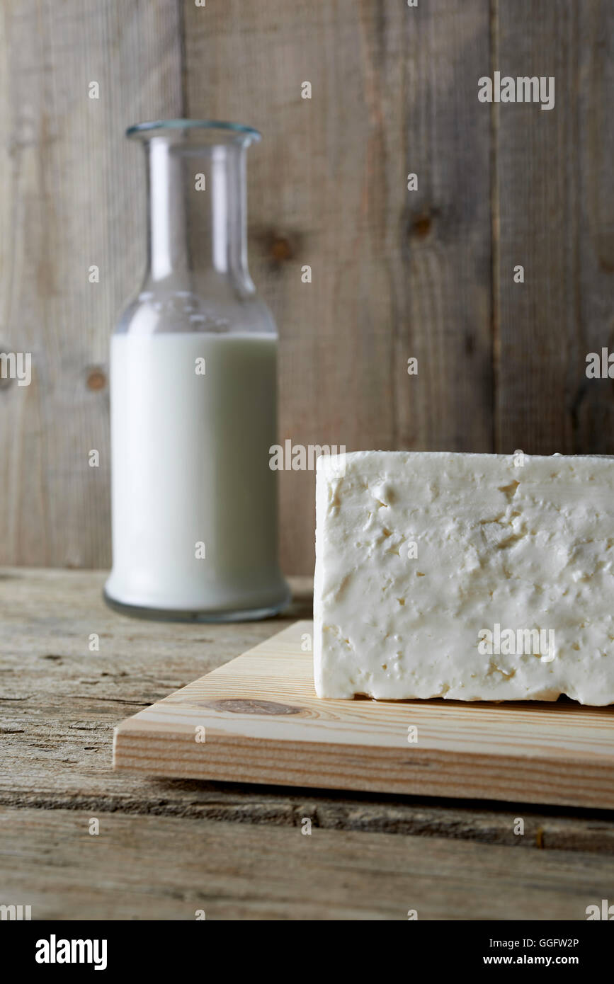 Frischer Schafskäse mit Flasche Milch auf einem Holztisch Stockfoto