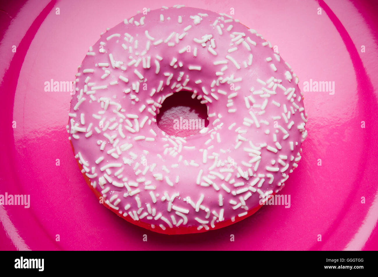 Glasierte rosa Donut auf einem rosa Platte Stockfoto