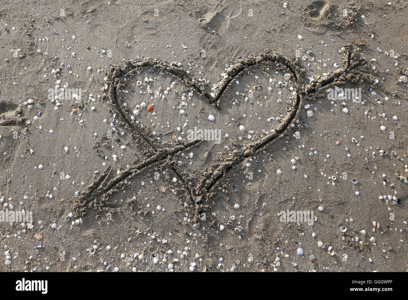 Herz-Symbol mit Pfeil gezeichnet am Strand Stockfoto