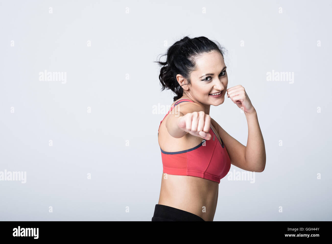 Die lächelnde junge Frau übt ihre Boxübung mit Smile Sand Selbstvertrauen. Kopieren Sie den Platz links neben dem Bild Stockfoto