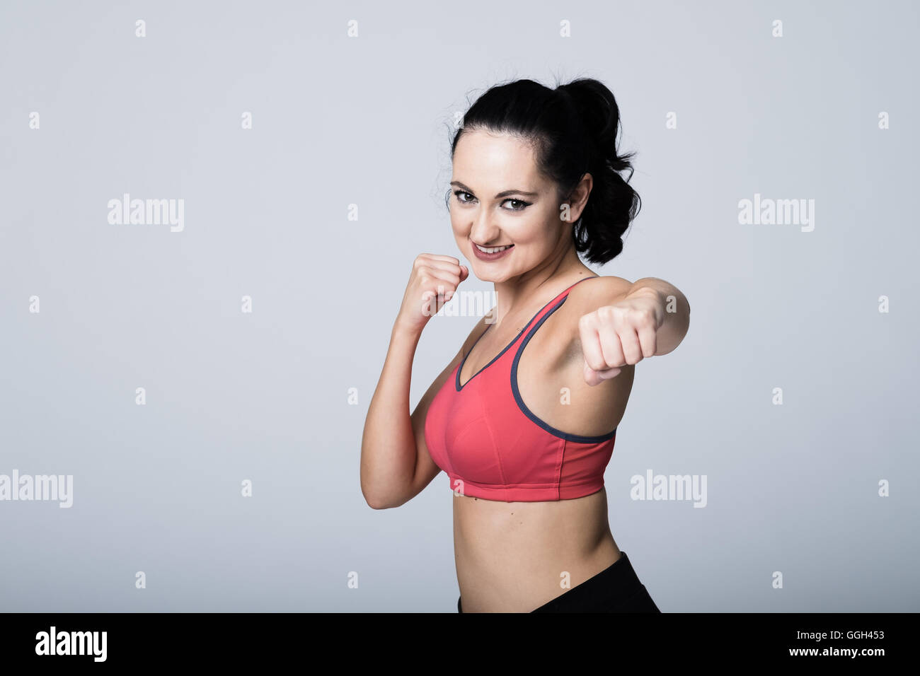 Junge fitte Frau, die Boxen während des Tragens von Fitnessgeräten übt. Weißer Hintergrund mit Kopierraum links Stockfoto